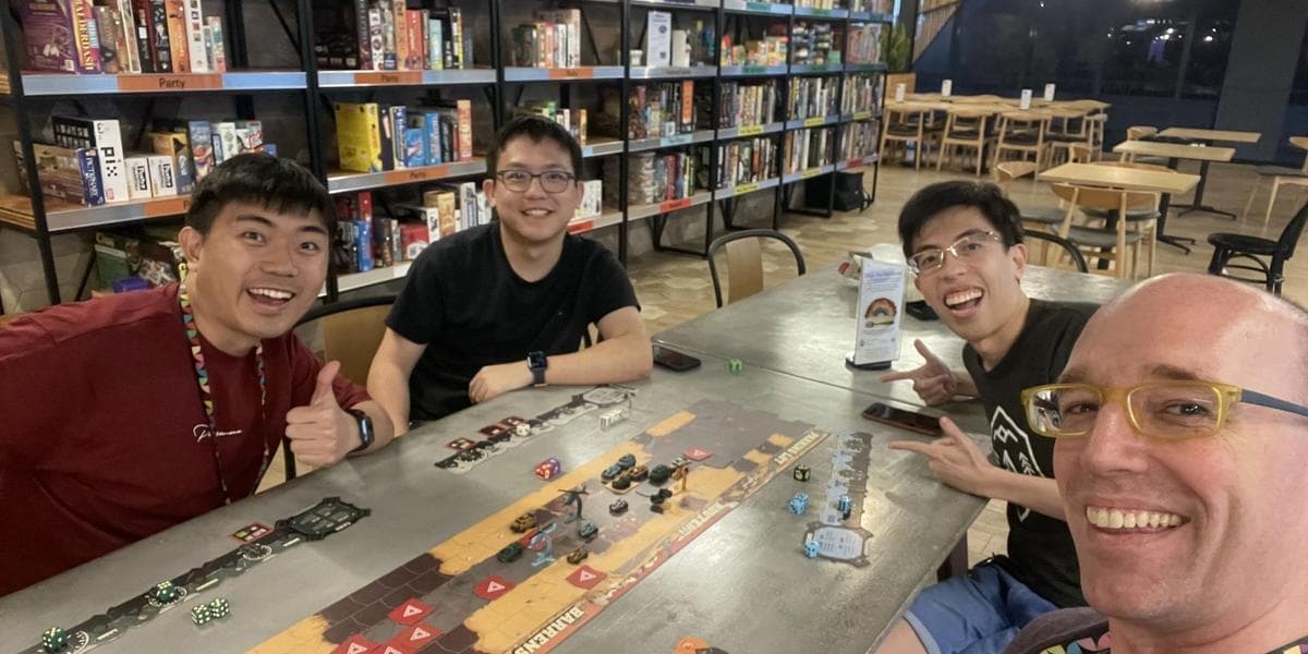 Brian with three other people playing a game at the board game cafe