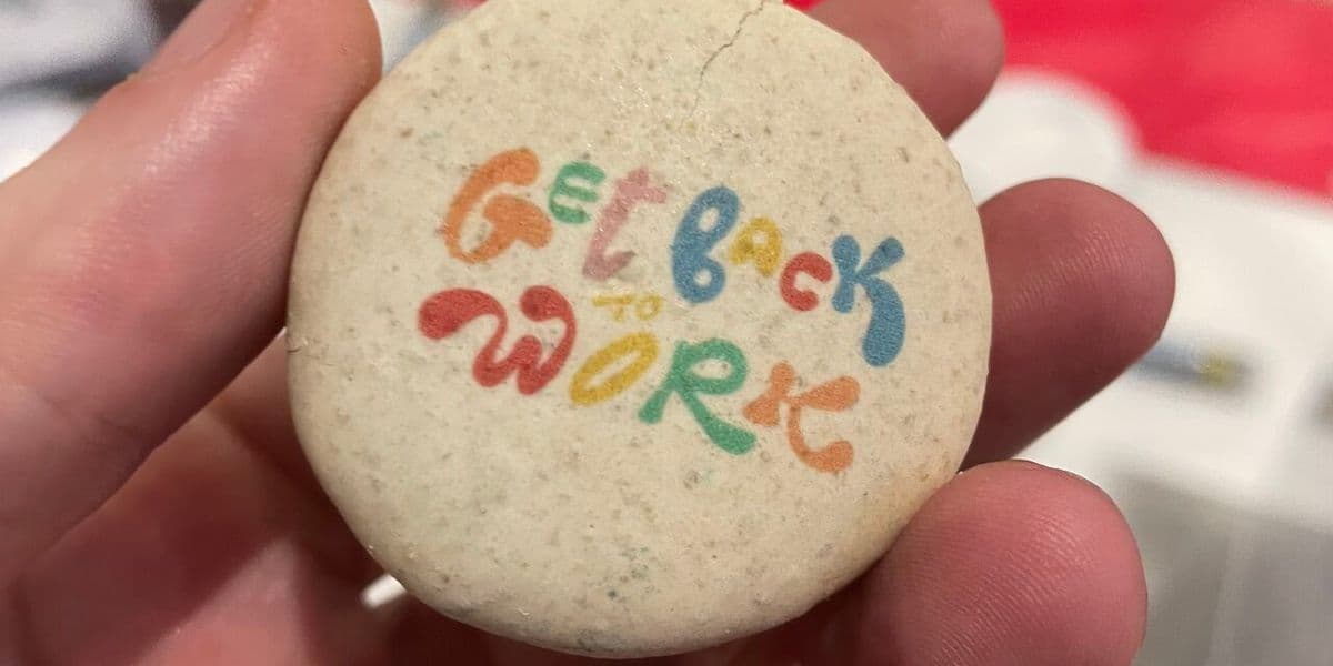 Gray pin with the words "Get back to work" on it